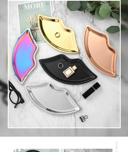 Detailed view of colorful lip-shaped metal jewelry trays on a white marble background