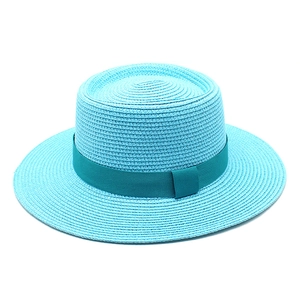 Detail of turquoise boater straw hat with matching dark cyan ribbon and woven texture