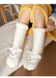 Close-up of fluffy white lamb wool floor socks featuring a cute cartoon alpaca design