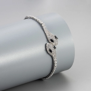 Detailed close-up of a silver snake bracelet with white crystals and black gem eyes