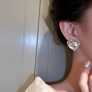Elegant silver heart clip-on earrings with shimmering rhinestones worn by a model