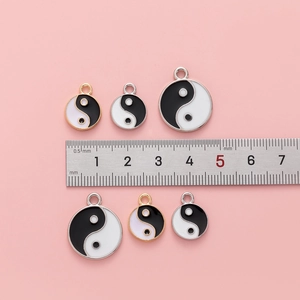 Yin Yang Tai Chi pendants in three sizes with black and white enamel on pink background