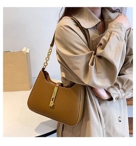 Detail of caramel brown faux leather underarm bag with elegant gold hardware and chain