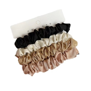 Set of 4 silk satin scrunchies in black, cream, gold and pink on display card