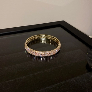 Close-up of three-row gold-plated bracelet with pave-set cubic zirconia on black base