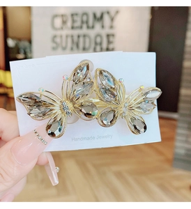 Macro detail of a 8cm butterfly hair clip with grey faceted crystals and gold frame