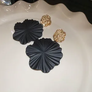 Übergroße schwarze Spiralblumen-Ohrringe mit goldenen gehärteten Metallsteckern auf Teller