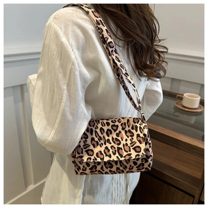 Detailed view of khaki leopard print shoulder bag worn by model in a home setting