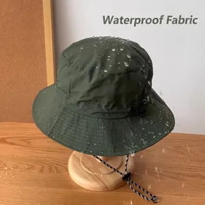 Waterproof dark green bucket hat with windproof cord on a wooden stand