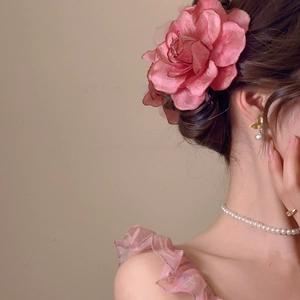 Detail of pink fabric flower hair clip with butterfly pearl earrings on a model