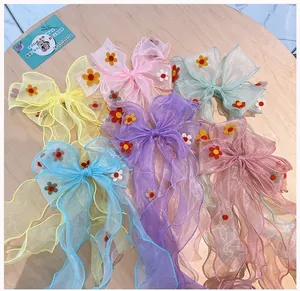 Close-up of colorful mesh bow hair clips with felt flowers on a light wood background
