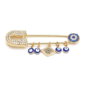 Detail of gold safety pin brooch with sparkling rhinestones and dangling evil eye charms