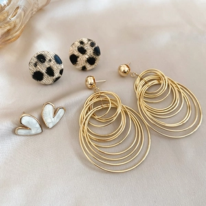 Detailed shot of leopard print studs and heart earrings on silk fabric background