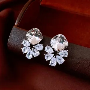 Boucles d'oreilles pendantes argentées avec zircons taille coussin et poire sur support brun
