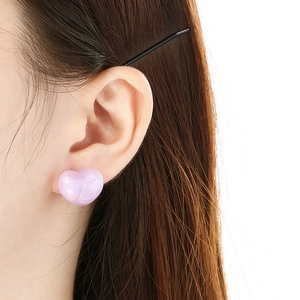 Nahaufnahme herzförmiger Ohrstecker in Hellviolett mit Perlmutt-Effekt am Modell