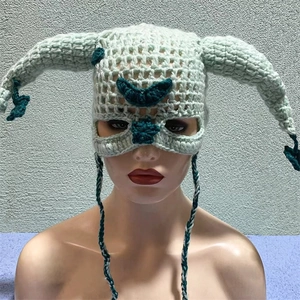 Detail of hand-crocheted green knit mask hat with long horns and woven tie straps