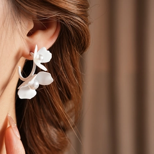 Close-up of elegant matte white floral earrings with pearls on a model side profile