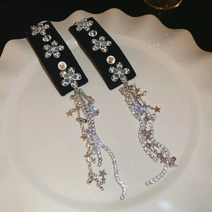 Detail of velvet hair clips with silver flower charms and long shimmering tassel chains