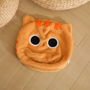 Cappello a gatto in peluche arancione con grandi occhi su fondo in legno caldo