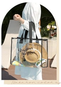 Outdoor shot of transparent PVC beach tote bag with straw hat and colorful towel inside