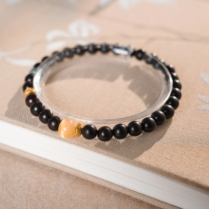 Close-up of sandalwood bead bracelet with yellow gemstone and gold metal spacers