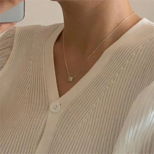 Close-up of elegant square zircon pendant necklace worn on woman's collarbone