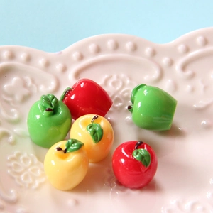 Miniature resin apples in red, green, and yellow displayed on a decorative plate
