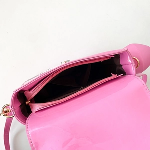 Interior view of the pink patent leather bag showing brown fabric lining and zipper pocket