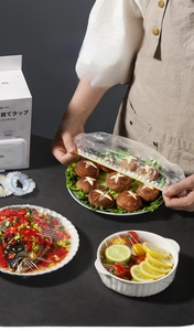 Detail of 100-piece pack disposable food covers showing elastic stretch on various bowls