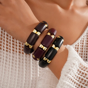 Close-up of three matte acrylic bracelets in burgundy and brown with gold metal rings