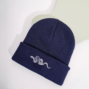 Detail of navy blue knit beanie featuring high-quality white snake pattern embroidery