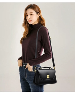 Close-up of elegant black leather flap bag with gold rotating lock and top handle
