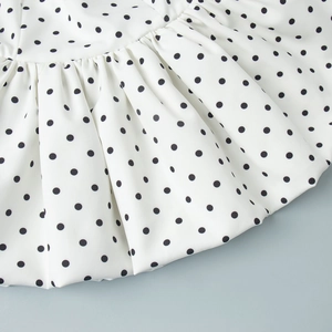 Vue détaillée du motif à pois noirs sur tissu blanc avec texture plissée élégante