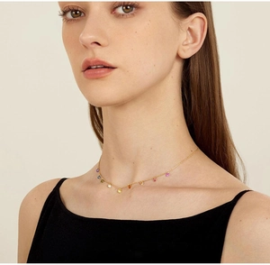Close-up of 18K gold-plated rainbow chain necklace worn by a model on plain background
