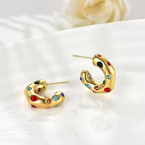 Detailed close-up of golden C-shaped hoop earrings with colorful inlaid crystals