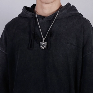 Silver shield pendant necklace with anchor motif on rope chain worn by a male model