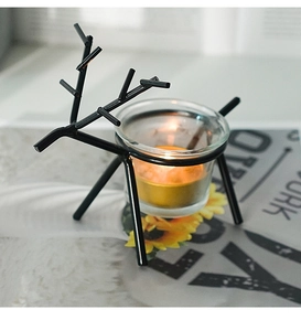 Detailed view of a black metal reindeer candle holder with a warm glass tealight cup