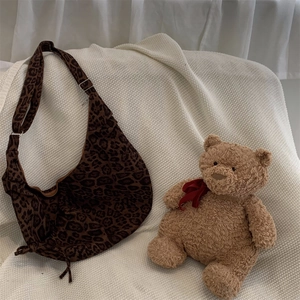 Detail of a brown leopard print crescent bag with adjustable strap and silver buckles