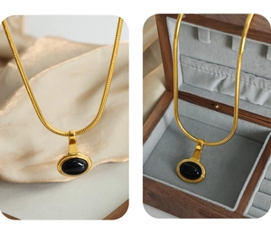 Detail of gold snake chain necklace with black oval gemstone pendant on silk