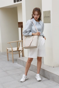 Beige tote bag with geometric print and metal chain strap shown in an outdoor lifestyle shot