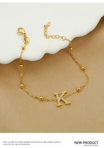 Close-up of gold titanium steel bracelet with sparkling zircon letter K charm detail