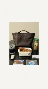Dettaglio della borsa termica marrone scuro con manico e set coordinato di scatola bento
