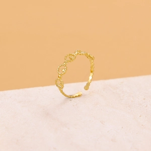 Detail of adjustable gold ring with linked circular chain texture on stone surface