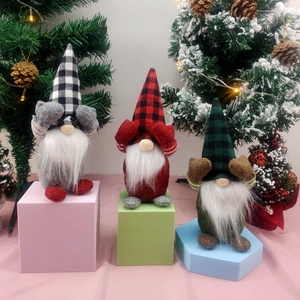 Three faceless Christmas gnomes in plaid hats sitting on colorful geometric stands