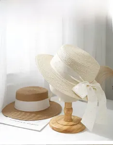 Detail of summer boater straw hats featuring delicate polka dot ribbons and chic bow accents