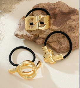 Detailed view of three minimalist gold metal hair ties with chain and knot designs