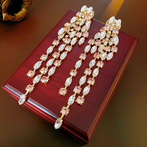 Macro shot of pink and white rhinestone tassel earrings on a red wooden jewelry box