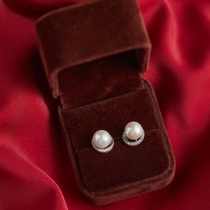 Close-up of white pearl earrings with silver diamond inlay in a premium jewelry box