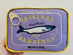 Close-up of purple sardine tin cosmetic bag showing detailed embroidery and yellow trim