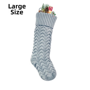 Detailed view of large light blue knit Christmas stocking with pine cones and gift box decor